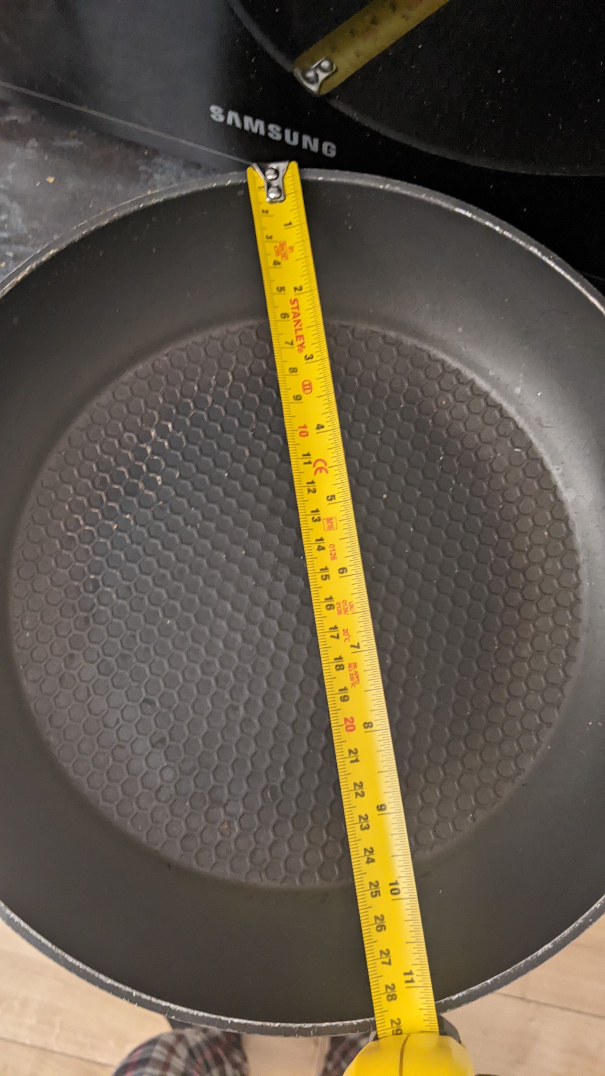 Picture of a frying pan with being measured with a measuring tape